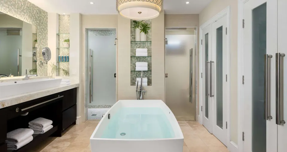 Bathroom in a luxury suite at Beaches Turks & Caicos with soaking tub, showers, vanity, and frosted doors.