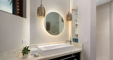Bathroom vanity in a luxury suite at Beaches Turks & Caicos with round lit mirror and vessel sink.