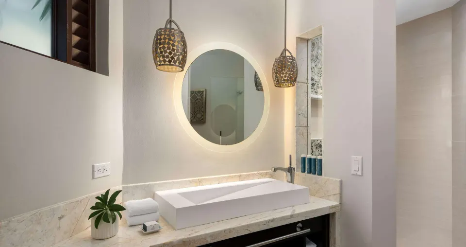 Bathroom vanity in a luxury suite at Beaches Turks & Caicos with round lit mirror and vessel sink.