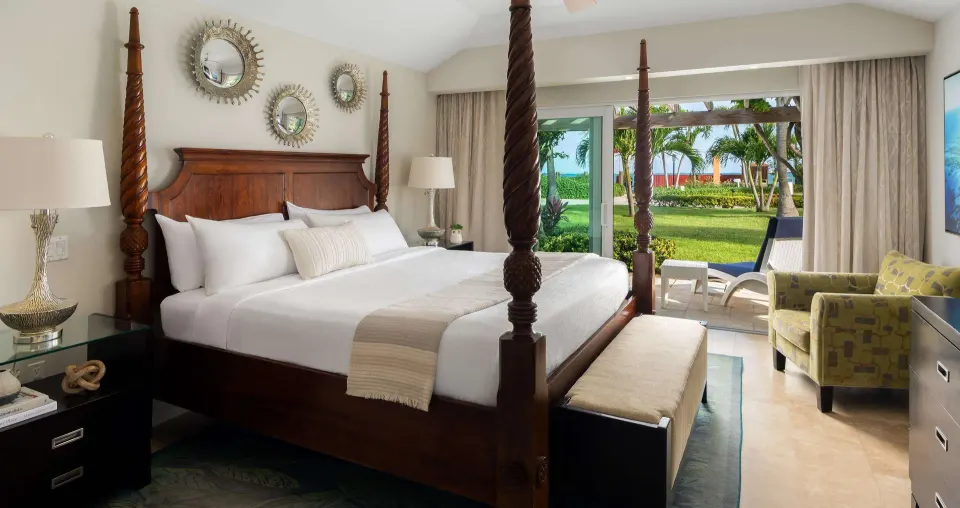 King bedroom in a luxury suite at Beaches Turks & Caicos with four-poster bed and patio view.