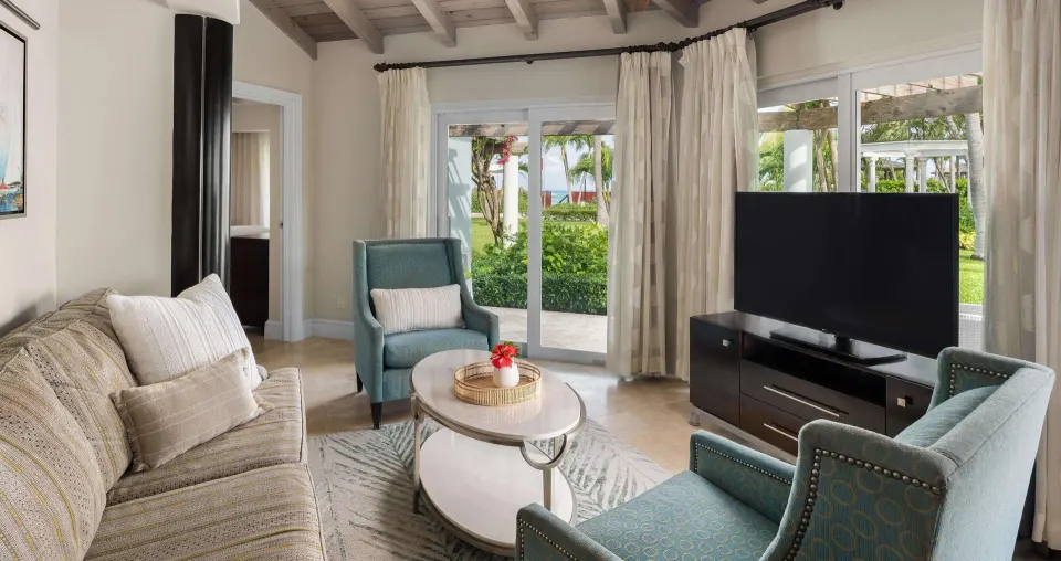 Living room in a luxury suite at Beaches Turks & Caicos with sofa, chairs, TV, and garden doors.