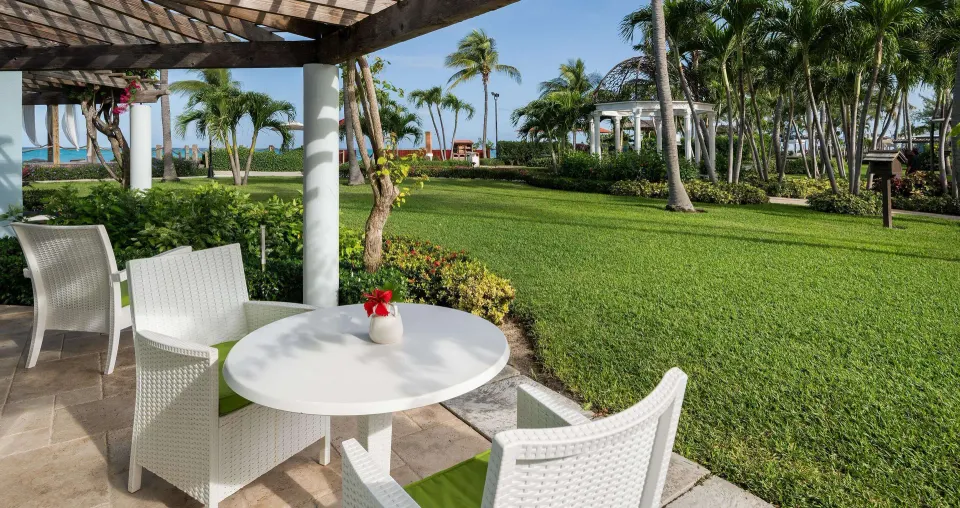 Patio for a luxury suite at Beaches Turks & Caicos with white chairs, table, lawn, palms, and ocean beyond.