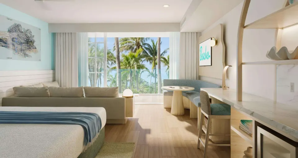 King bed, sofa, desk, and palm view in a suite at Beaches Turks & Caicos.