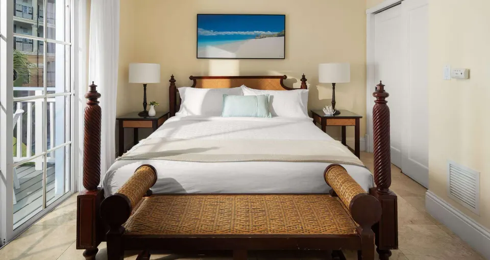 Garden view suite bedroom with wicker bench and balcony doors at Beaches Turks & Caicos.