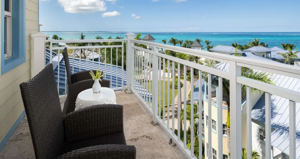 Ocean-view suite balcony with wicker chairs and turquoise water at Beaches Turks & Caicos.