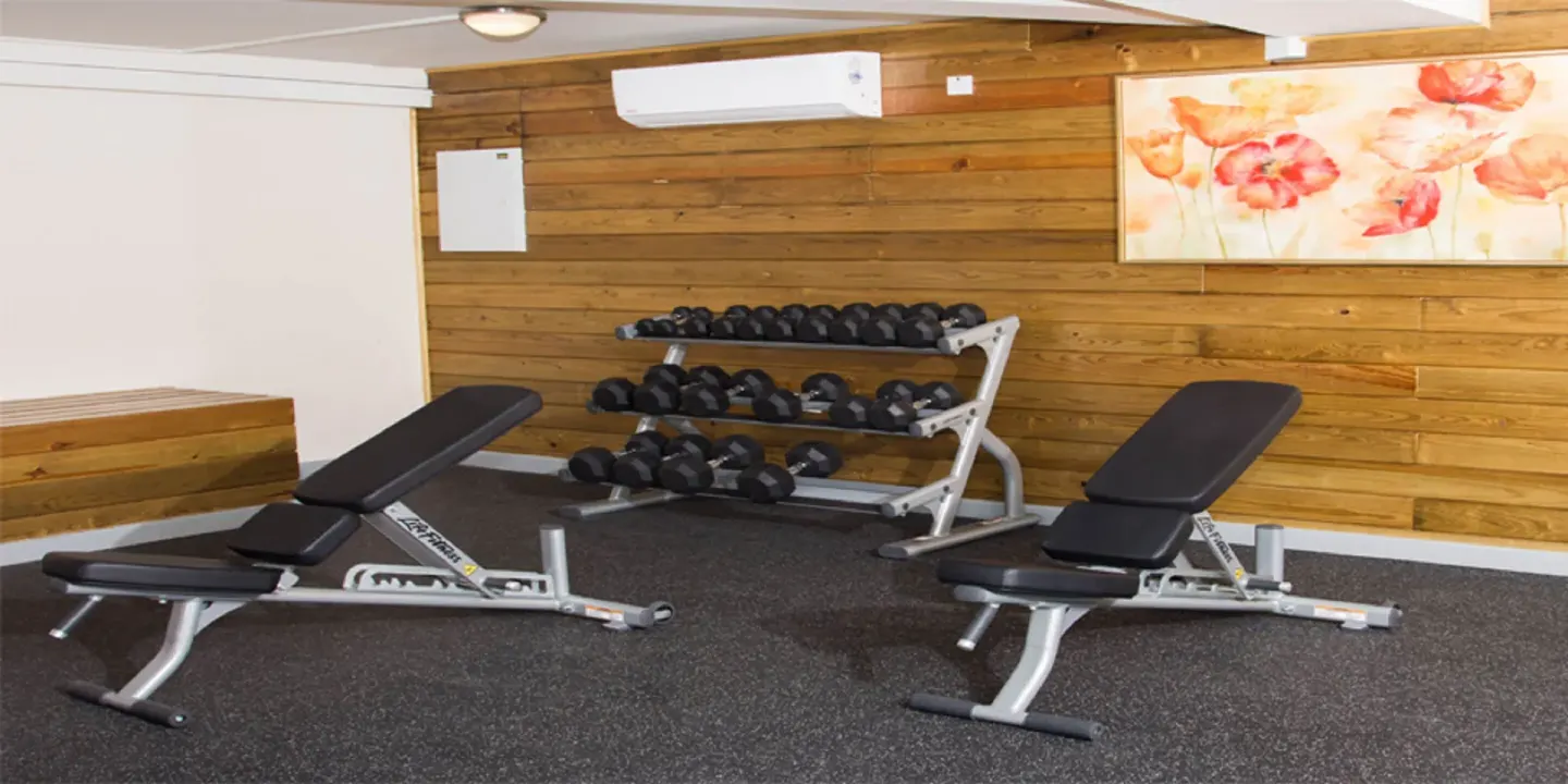 Fitness room with dumbbells and adjustable benches at Bel Jou Hotel.
