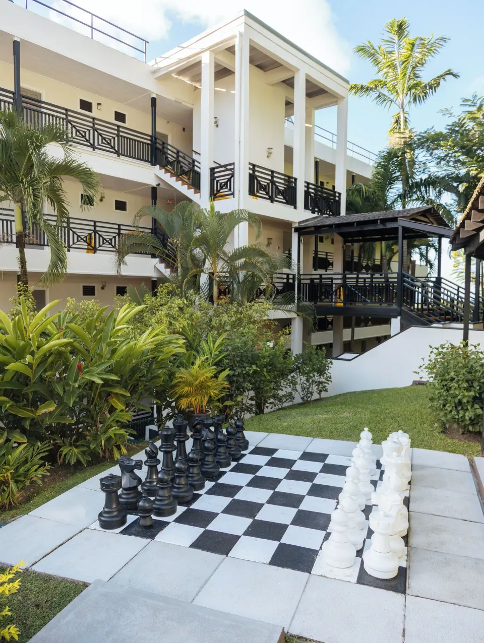 Garden chessboard with oversized pieces below guest balconies at Bel Jou Hotel.