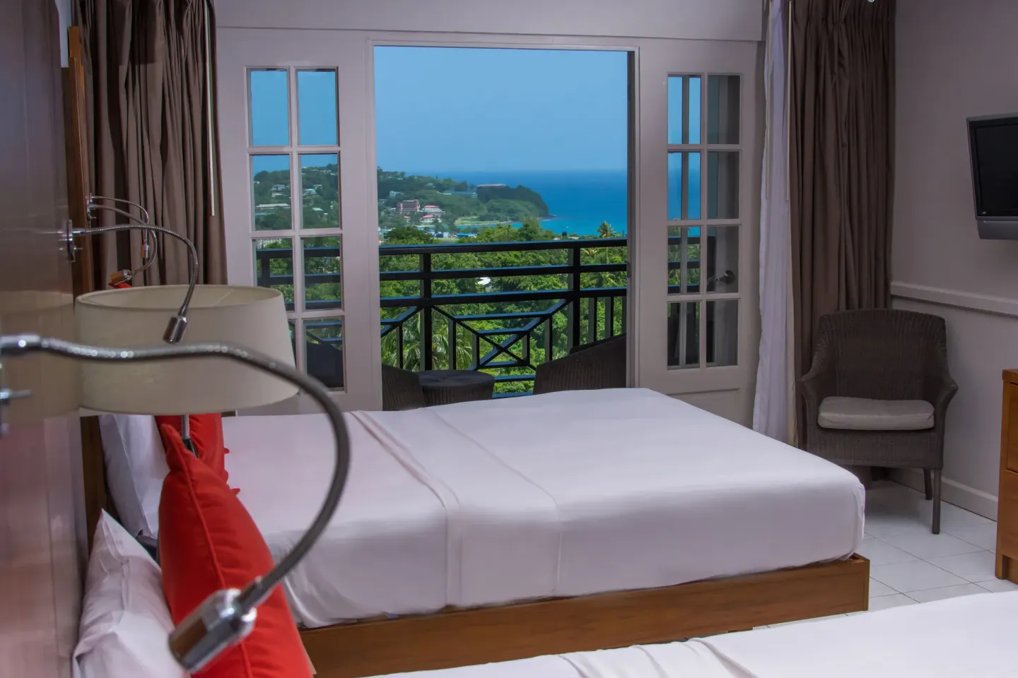 Guest room with bed, balcony doors, and blue sea view at Bel Jou Hotel.