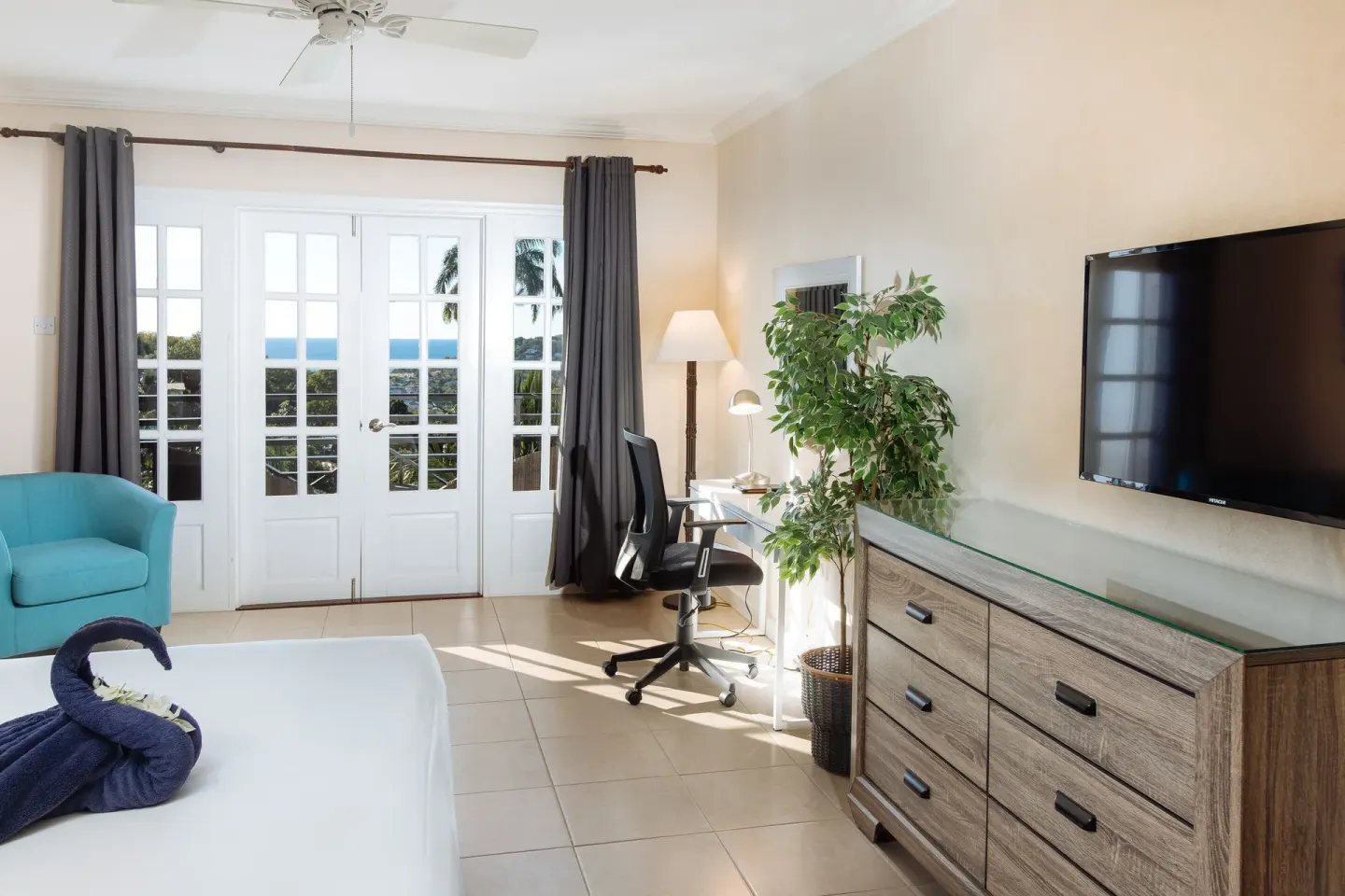 Guest room with bed, desk, TV and French doors at Bel Jou Hotel.