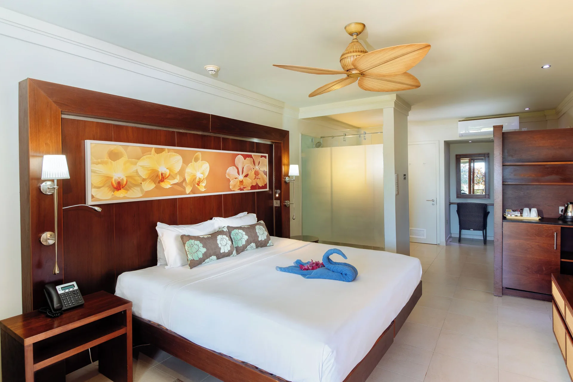 King-bed guest room with orchid wall art and wood furniture at Bel Jou Hotel.