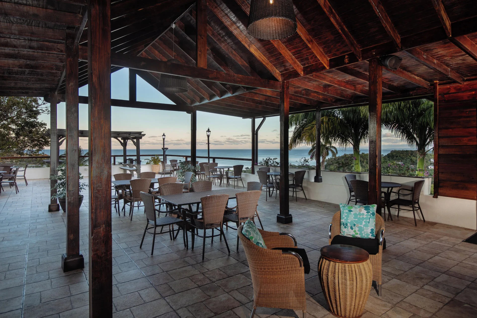 Open-air terrace with tables, lounge chairs, and sea views at Bel Jou Hotel.