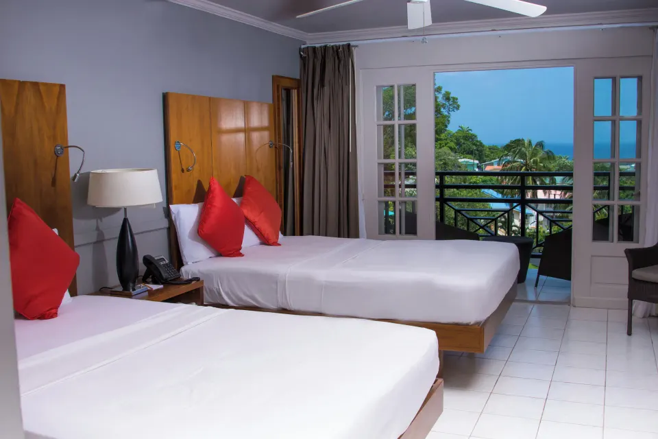 Partial Ocean View room with twin beds, balcony doors, and sea view at Bel Jou Hotel.