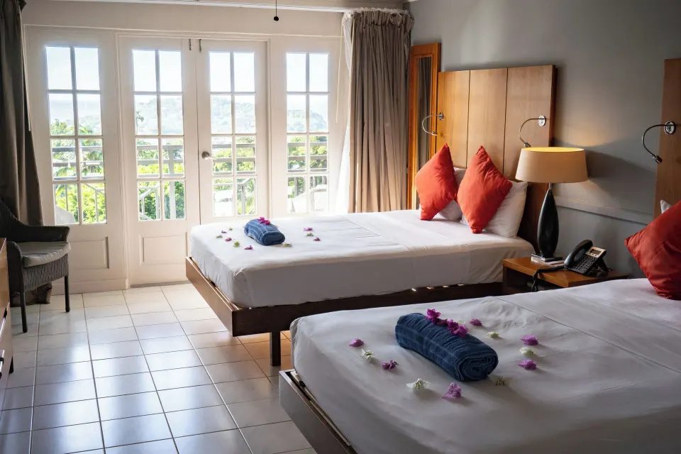 Partial Ocean View twin beds with flower accents and French doors at Bel Jou Hotel.