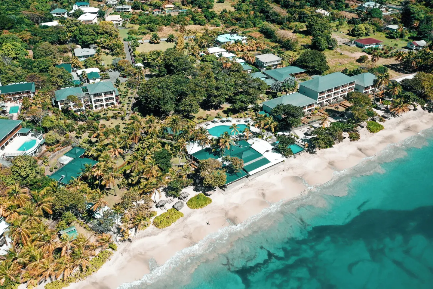 Aerial view of Bequia Beach Hotel along the sandy shoreline and turquoise sea.