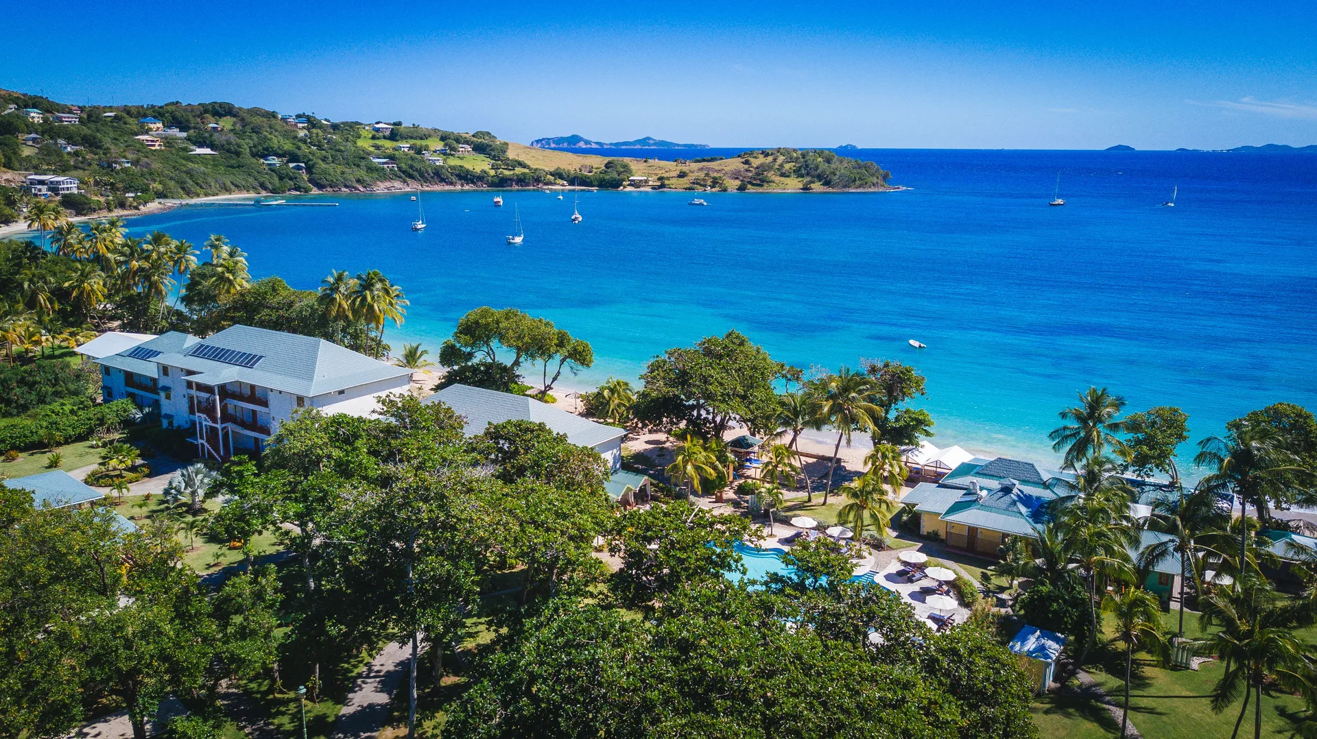 Aerial view of Bequia Beach Hotel grounds overlooking a blue bay with sailboats.