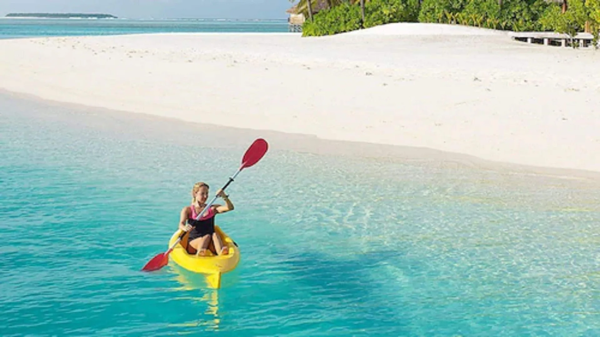 Kayaker paddling in clear turquoise water by the beach at Bequia Beach Hotel.