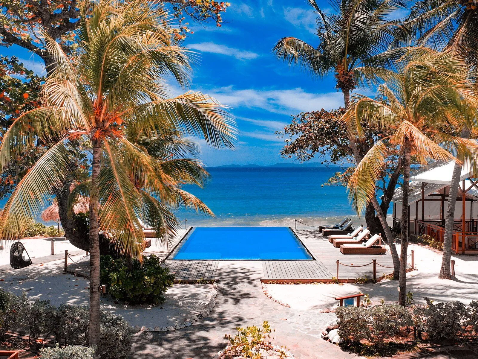 Beachfront pool framed by palms and sea at Bequia Beach Hotel.