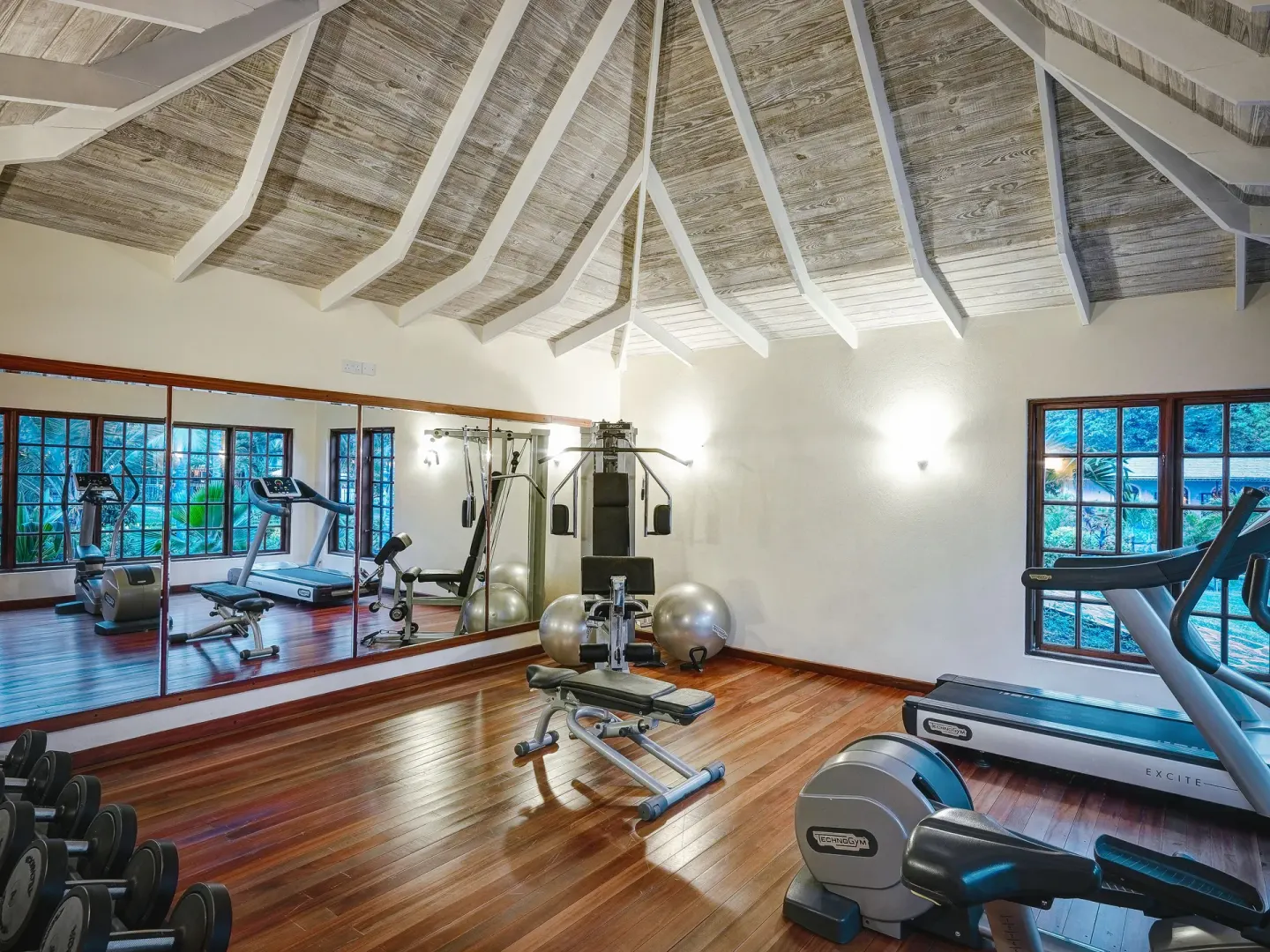 Fitness room with cardio machines, weights and mirrors at Bequia Beach Hotel.