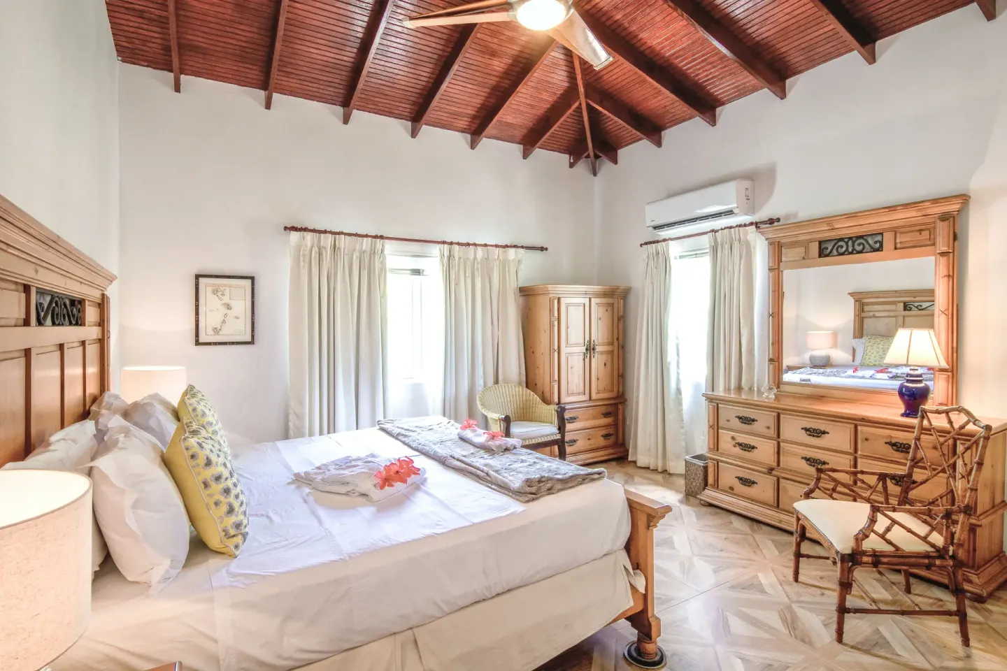 King bed, wood furniture, and vaulted ceiling in a guest room at Bequia Beach Hotel.