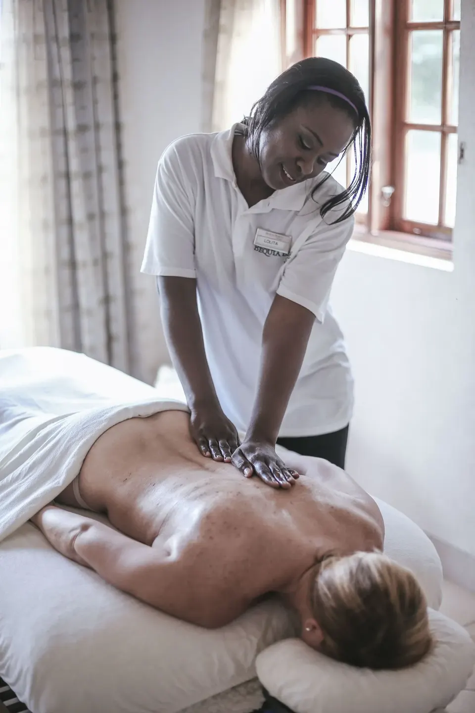 Therapist giving a back massage in a treatment room at Bequia Beach Hotel.