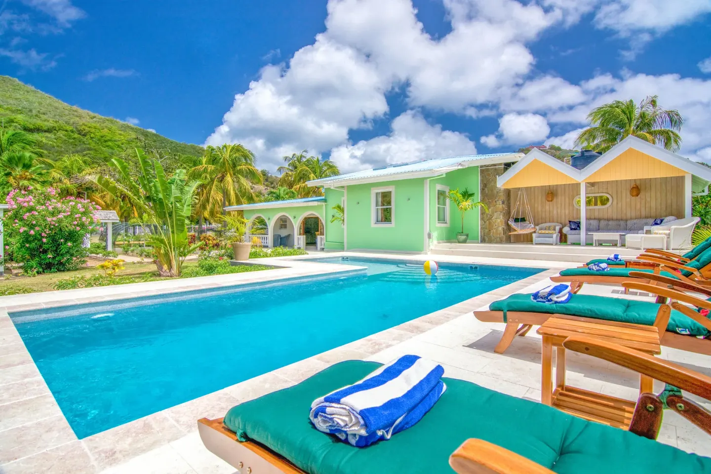 Private pool with loungers and a pastel villa building at Bequia Beach Hotel.