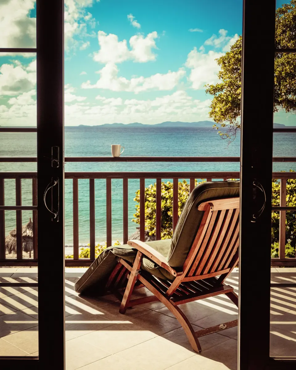 Balcony chair overlooking the sea through open doors at Bequia Beach Hotel.