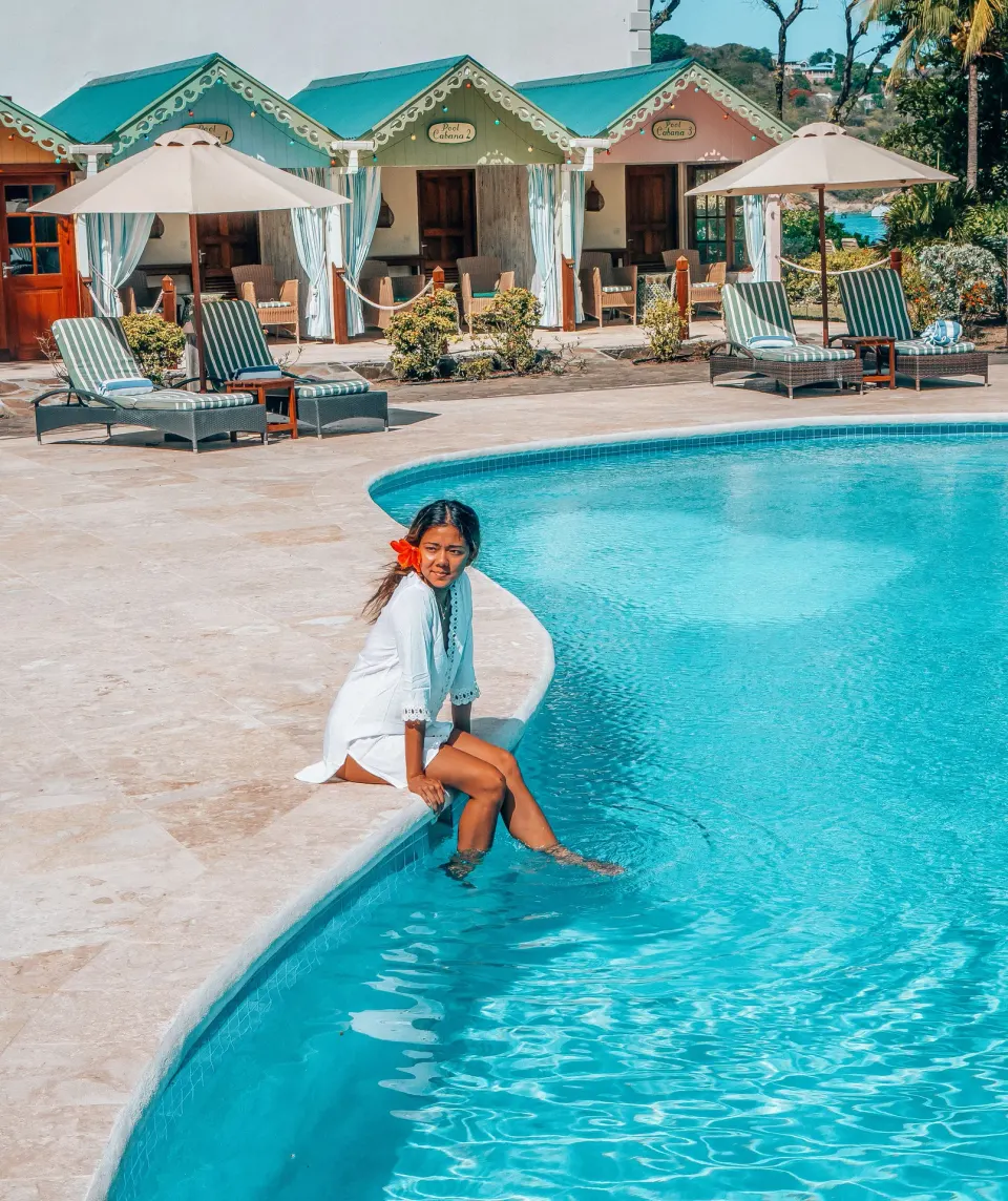 Guest sitting by the swimming pool with cabanas at Bequia Beach Hotel.