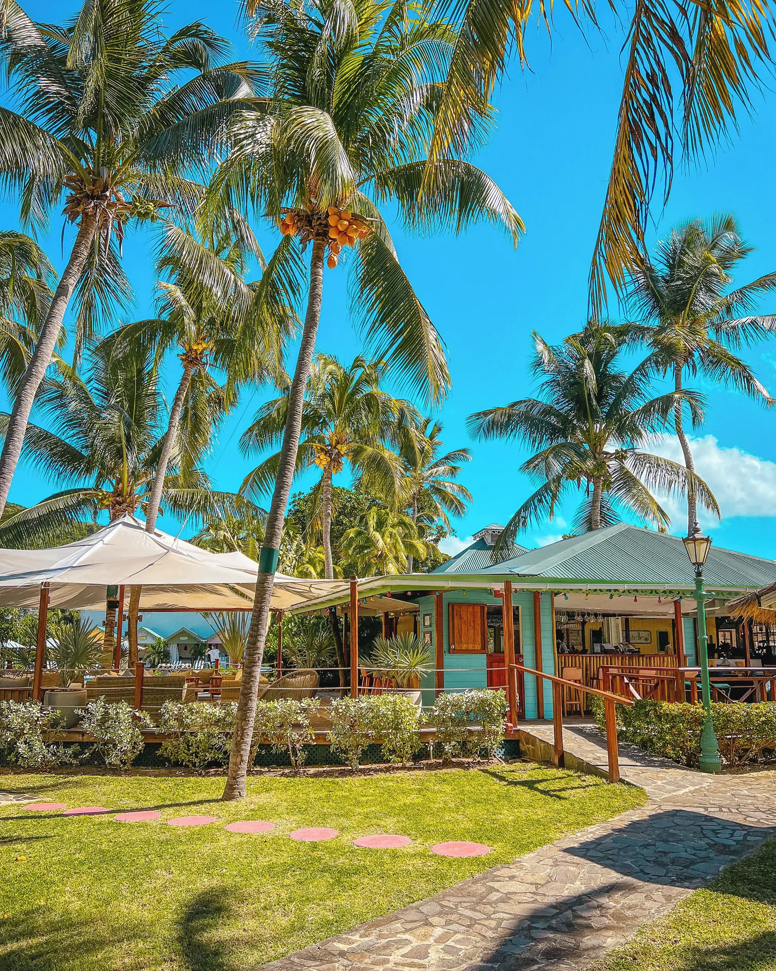 Tropical restaurant building and patio beneath coconut palms at Bequia Beach Hotel.