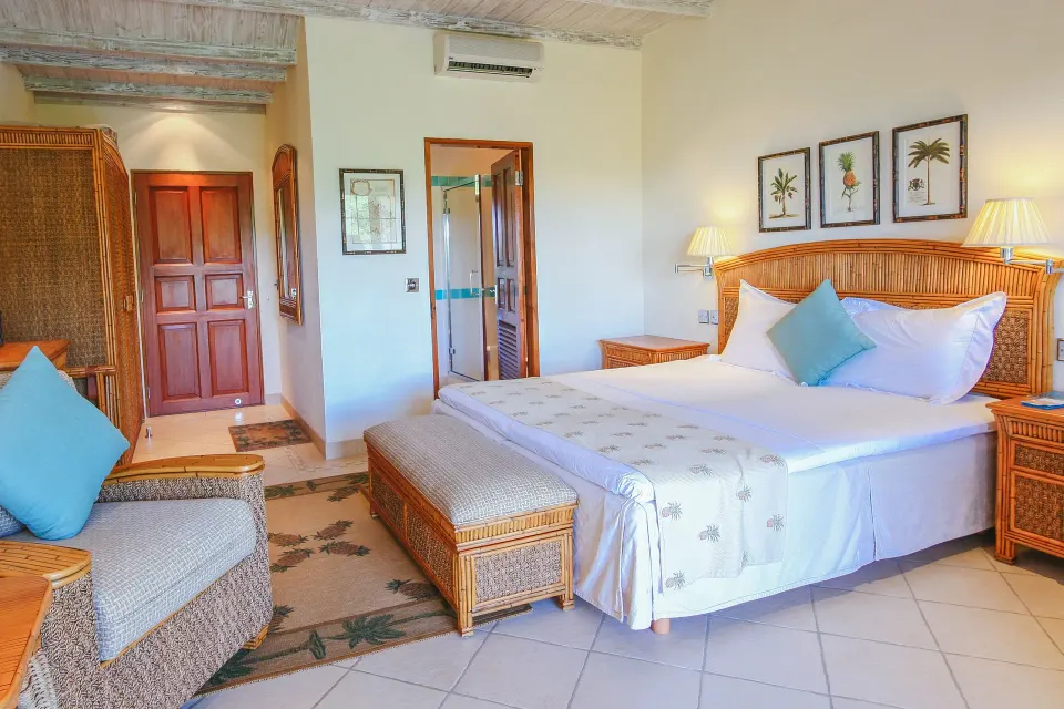 Classic Room king bed, lounge chair and open bathroom doorway at Bequia Beach Hotel.