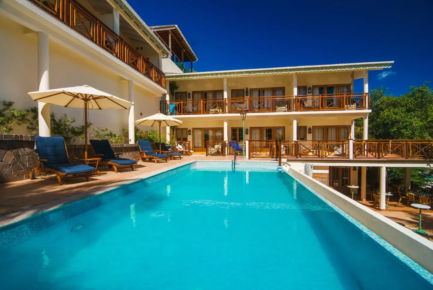 Pool beside balconies and sun loungers near Classic Rooms at Bequia Beach Hotel.