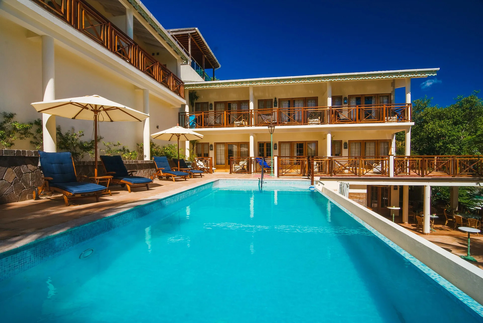Pool beside balconies and sun loungers near Classic Rooms at Bequia Beach Hotel.