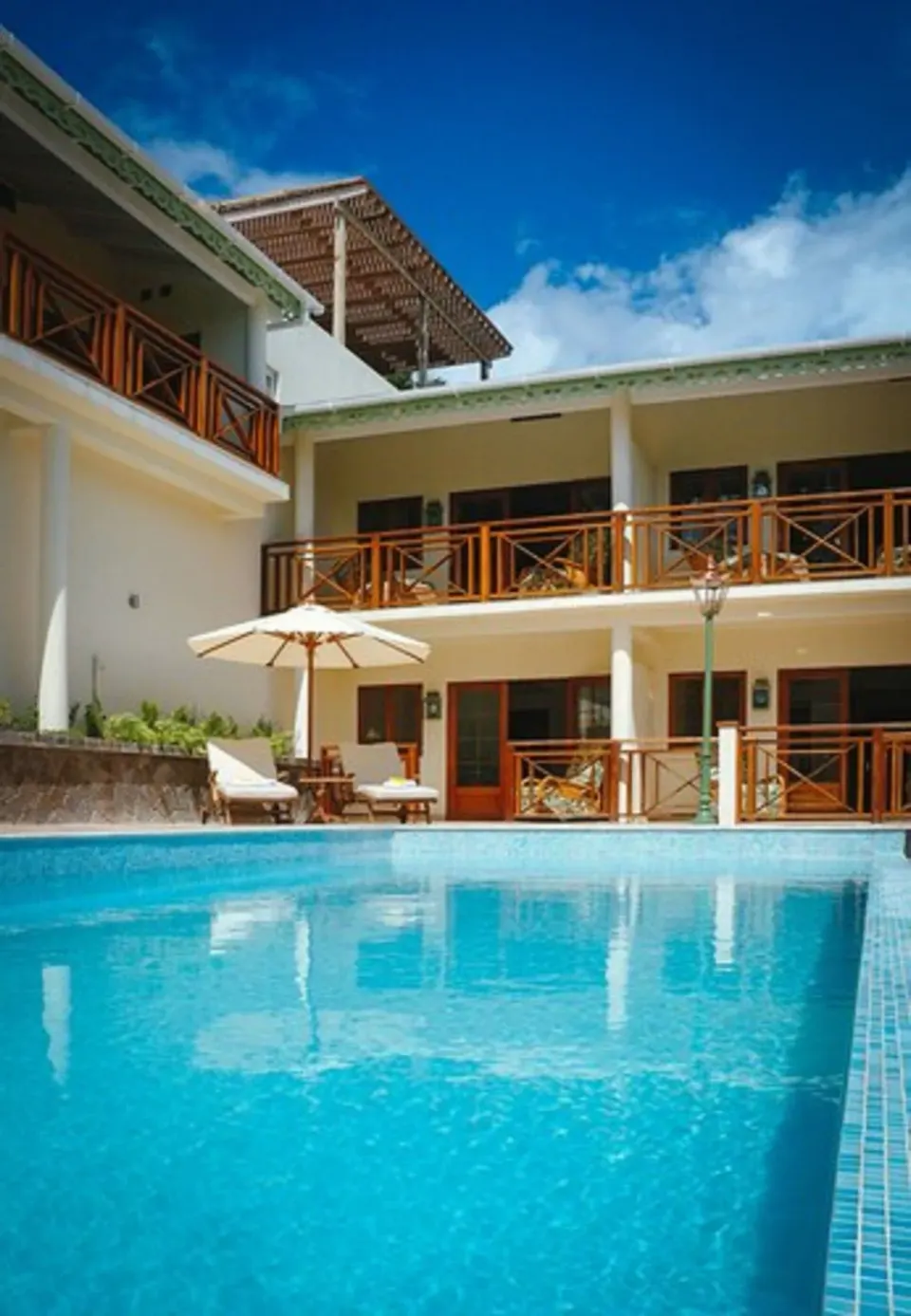 Pool edge, parasol and room balconies by Classic Rooms at Bequia Beach Hotel.