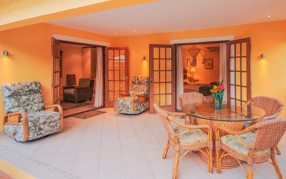 Covered terrace of a two-bedroom cottage at Bequia Beach Hotel with wicker dining and lounge seating.