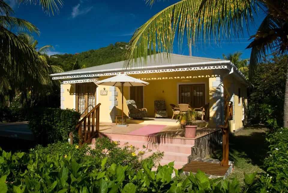 Yellow two-bedroom cottage terrace at Bequia Beach Hotel with private pool partly visible beside gardens.