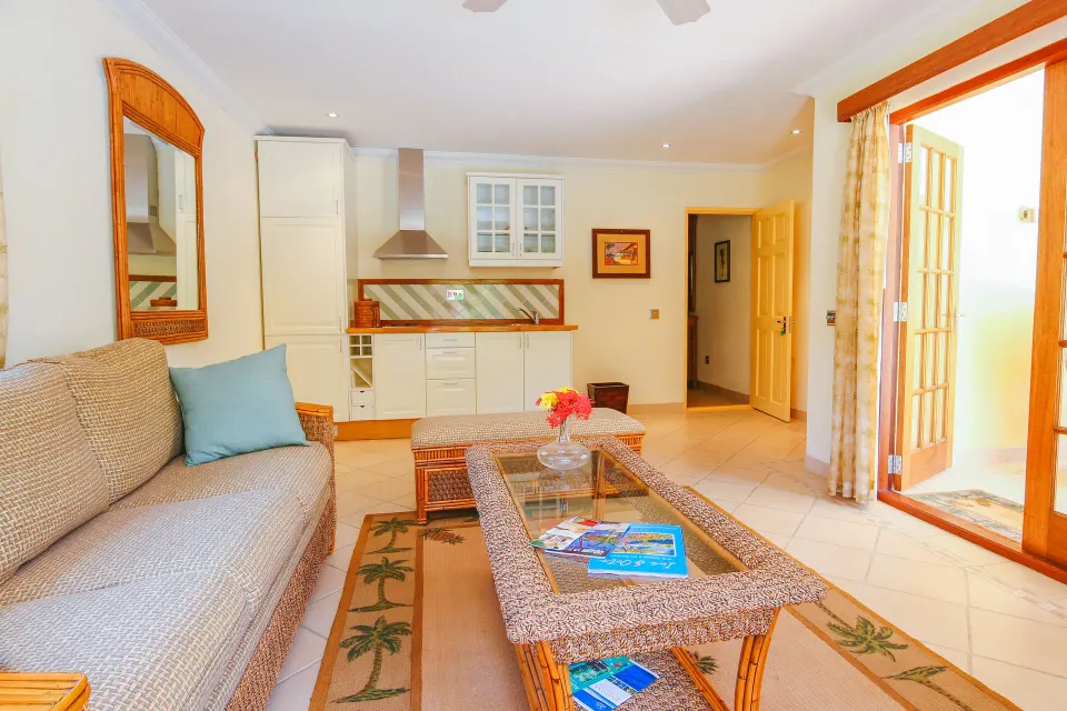 Living room and kitchenette in a two-bedroom cottage at Bequia Beach Hotel with open French doors.