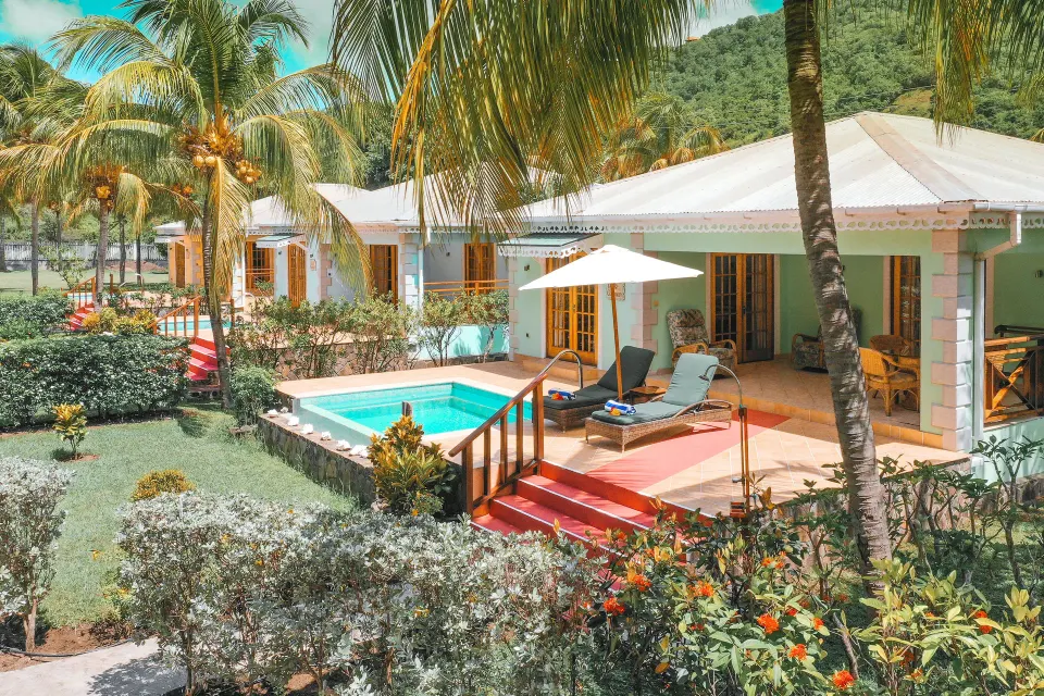 Two-bedroom cottage private pool and sun loungers at Bequia Beach Hotel surrounded by palms.