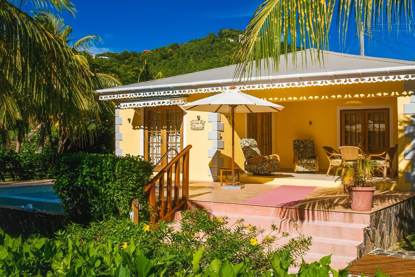 Two-bedroom cottage terrace and private pool at Bequia Beach Hotel framed by palms and gardens.