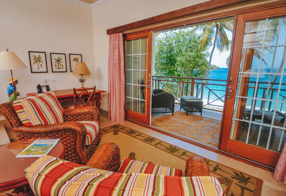 Beachfront room sitting area opening to an ocean-view balcony at Bequia Beach Hotel.