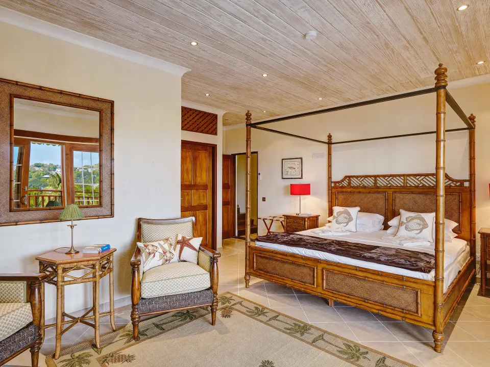 Grand Villa four-poster king bedroom with seating at Bequia Beach Hotel.