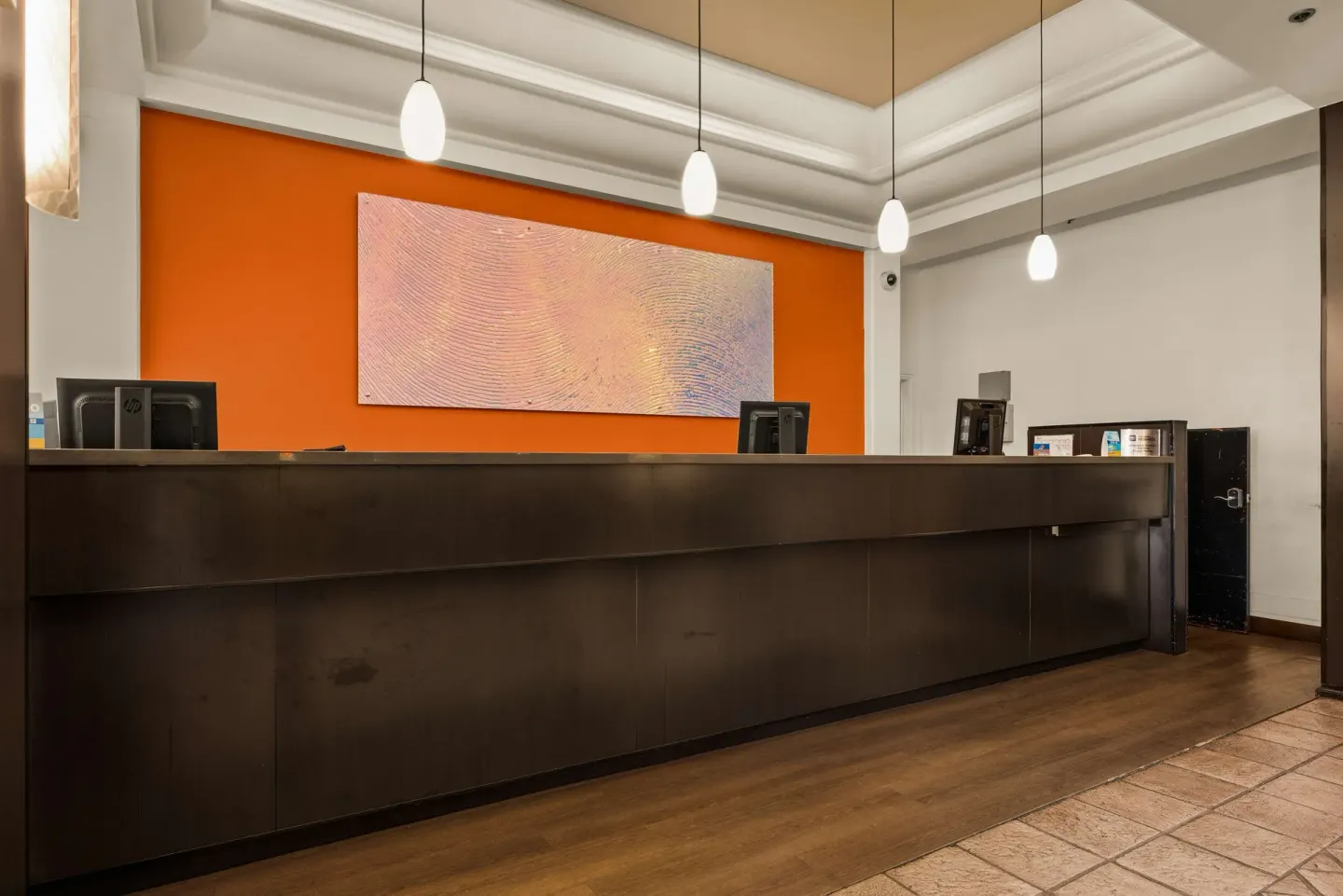 Front desk with orange accent wall at Best Western The Plaza Hotel Honolulu Airport.