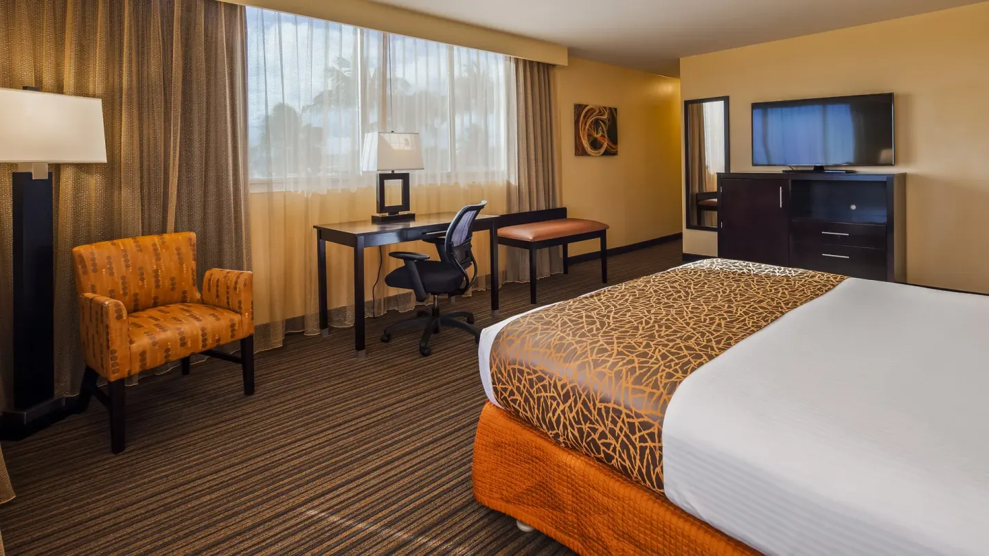 King bed guest room with desk and seating at Best Western The Plaza Hotel Honolulu Airport.