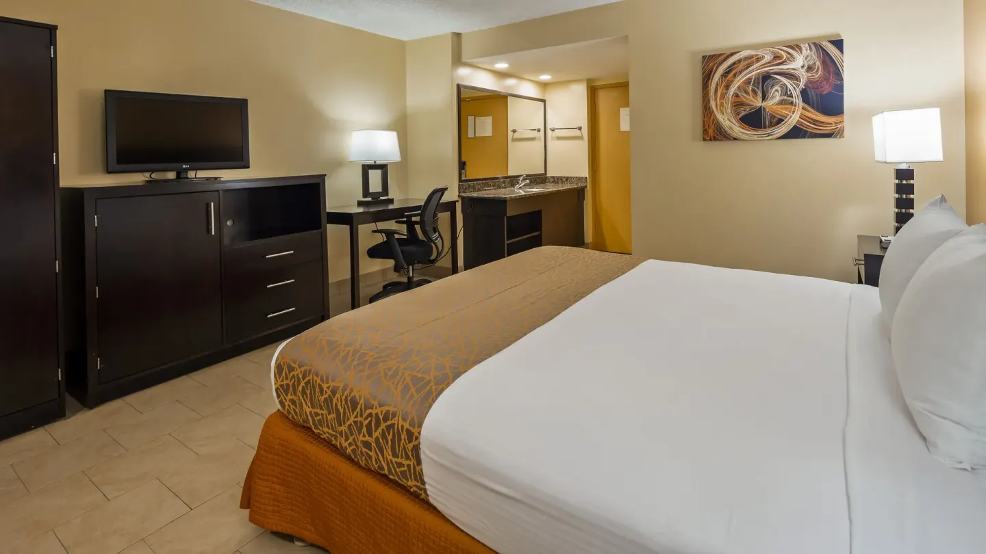 King bed guest room with desk and vanity at Best Western The Plaza Hotel Honolulu Airport.