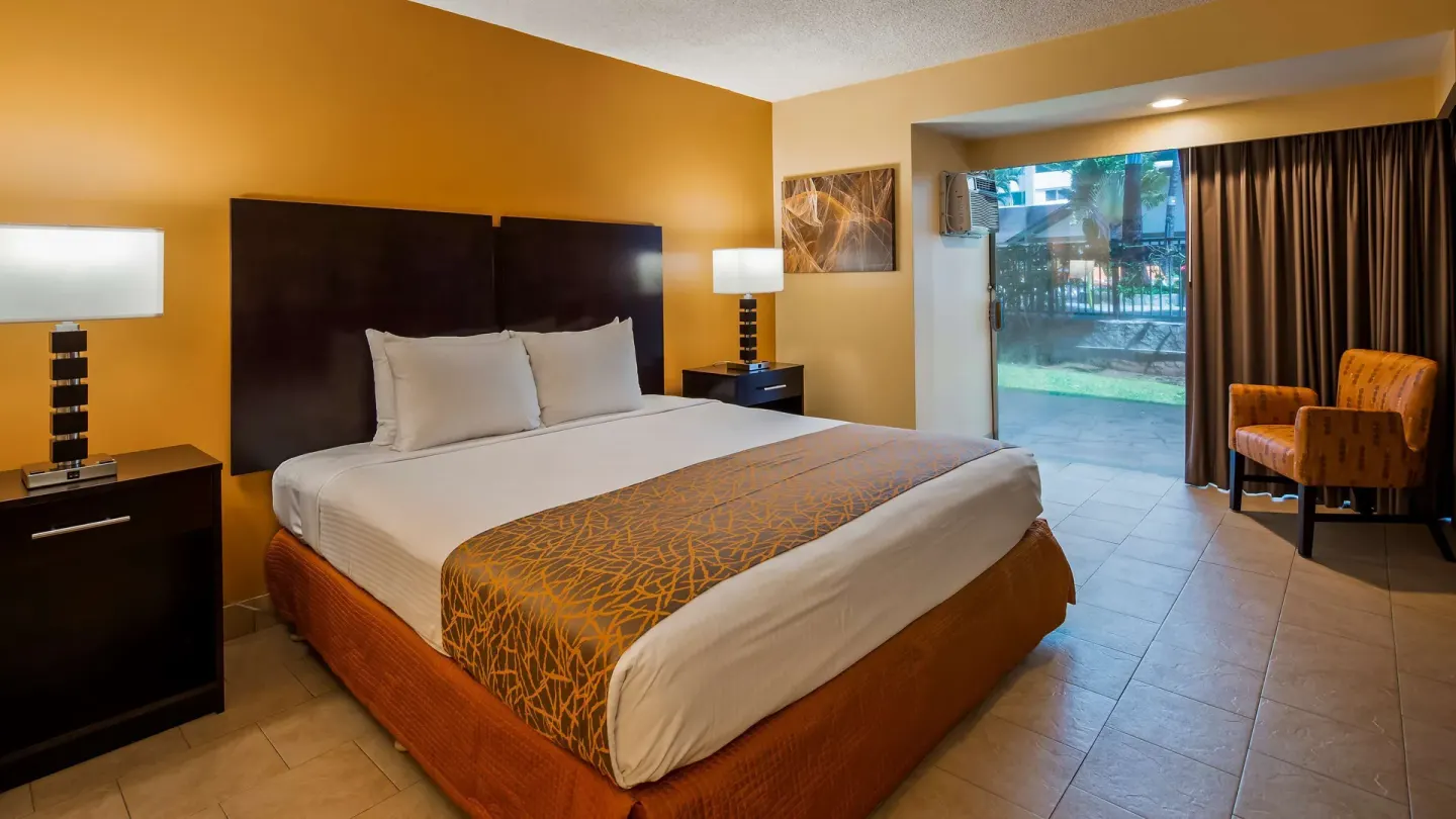 King bed guest room with tile floor and patio door at Best Western The Plaza Hotel Honolulu Airport.