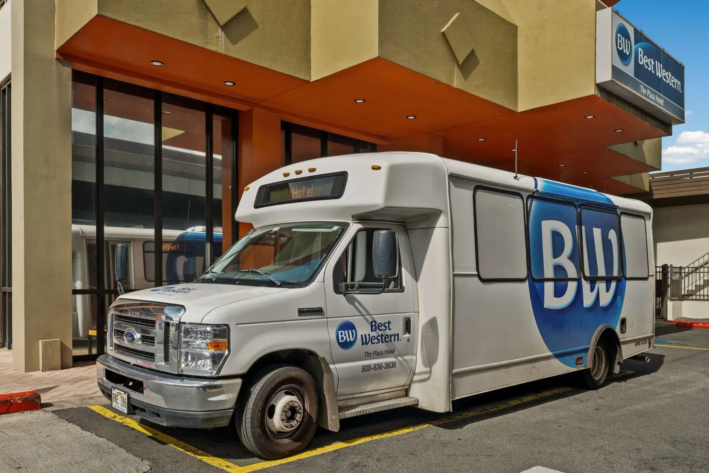 Hotel shuttle parked at the entrance of Best Western The Plaza Hotel Honolulu Airport.