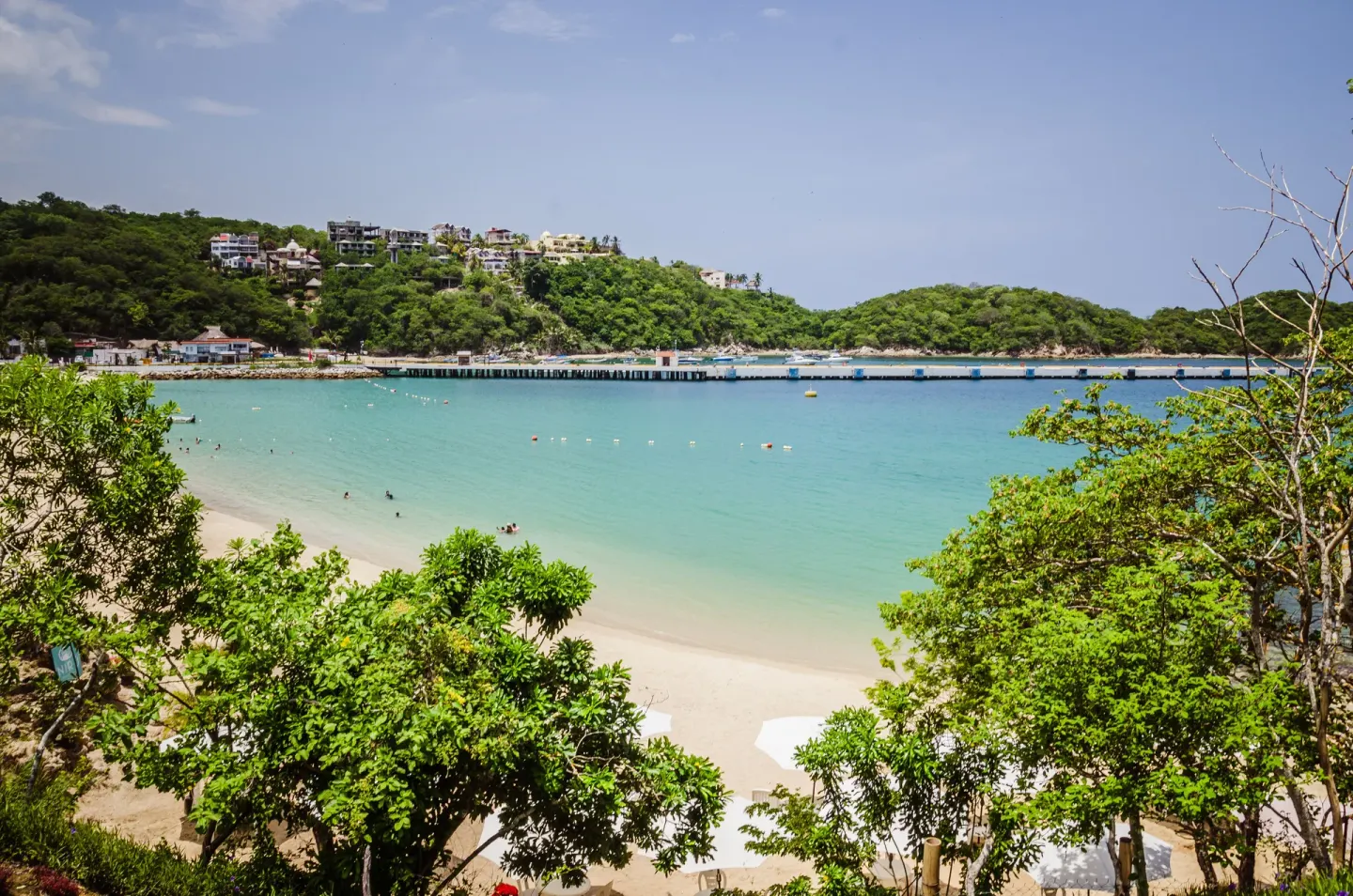 Bay, beach, pier, and green hills near Binniguenda Huatulco & Beach Club.