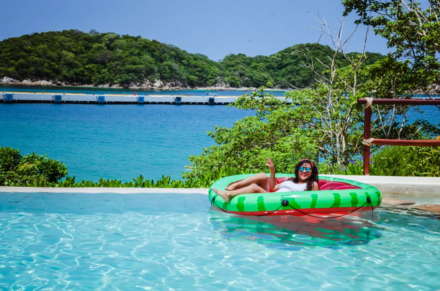 Guest floating in a pool overlooking the bay at Binniguenda Huatulco & Beach Club.