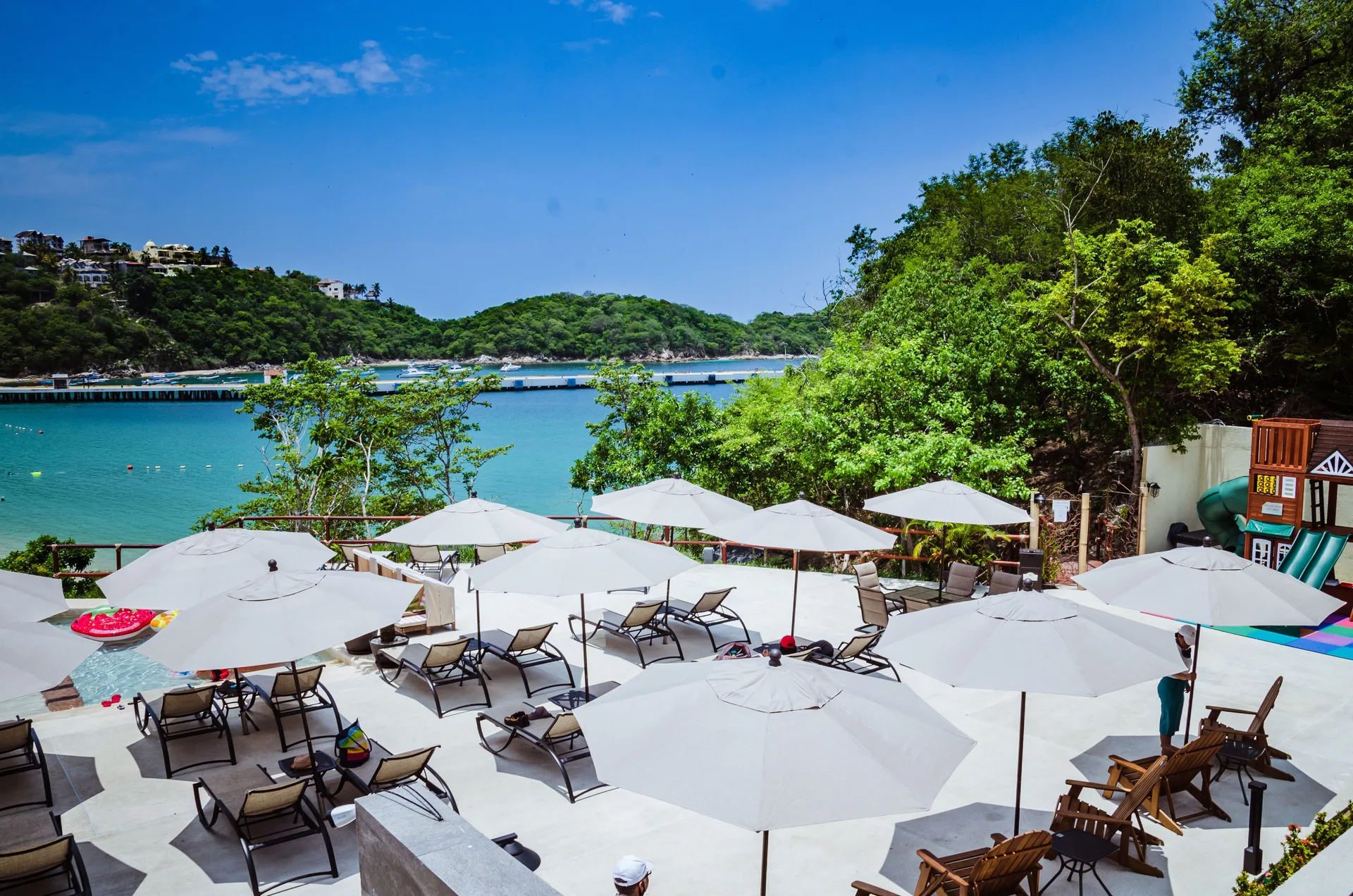 Beach club terrace with umbrellas and bay views at Binniguenda Huatulco & Beach Club.
