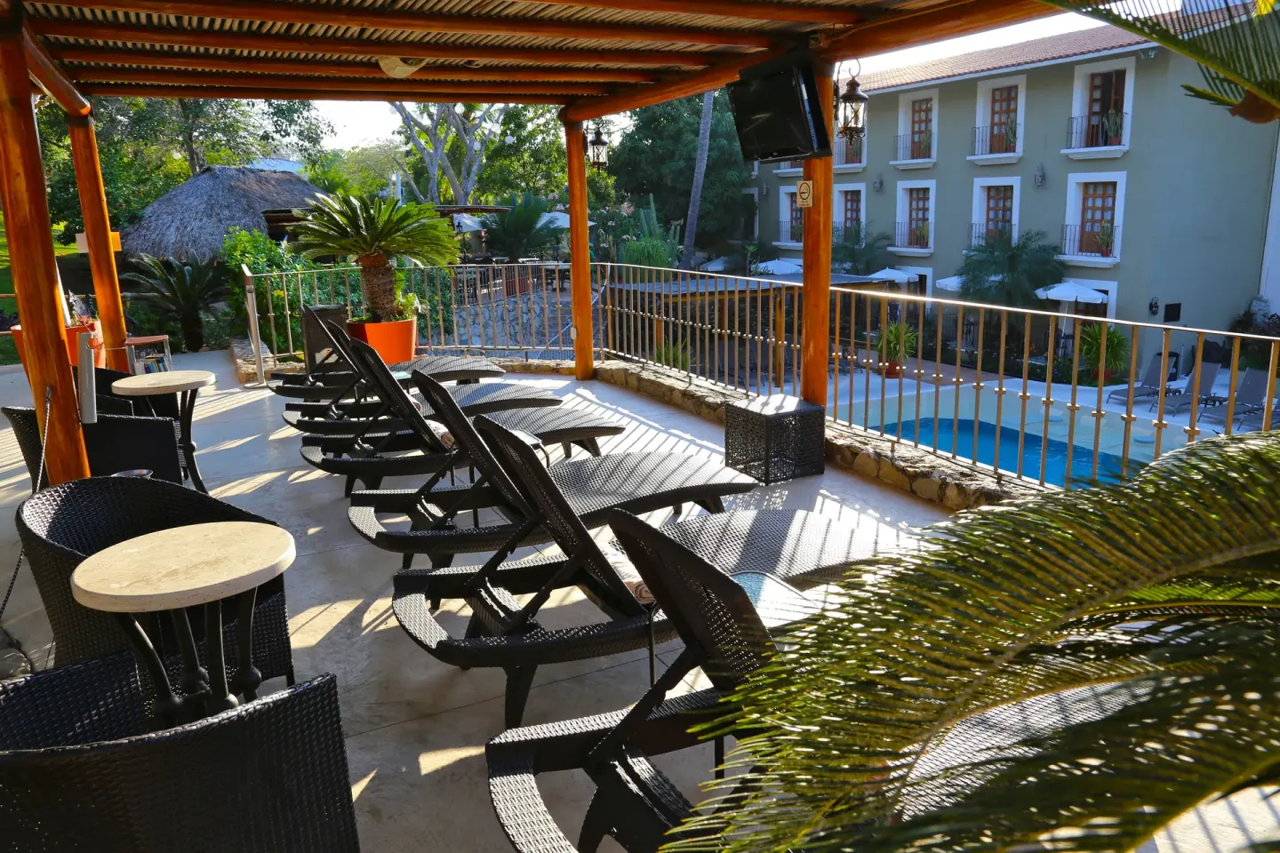 Covered terrace with loungers overlooking the pool at Binniguenda Huatulco & Beach Club.