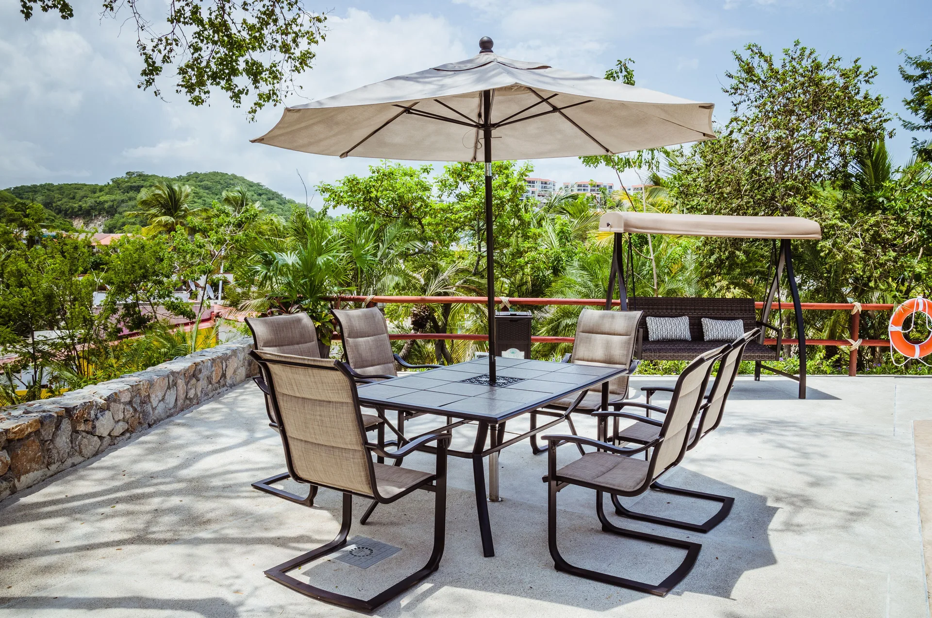 Terrace seating with umbrella and swing at Binniguenda Huatulco & Beach Club.