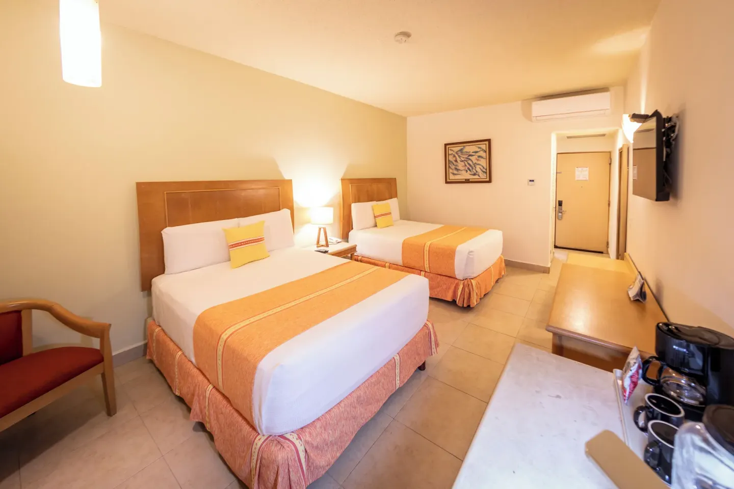 Guest room with two beds at Binniguenda Huatulco & Beach Club, plus desk, TV, and coffee setup.